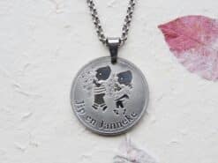 Zilveren muntketting met afbeelding van Jip en Janneke en tekst, aan zilveren ketting.