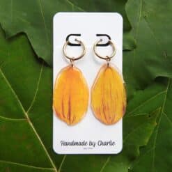 Dahlia oorringen met goudkleurige ringen en ovale hangers in oranje, geel en rood, opDisplaykaart.