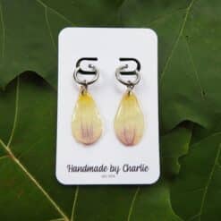 Dahlia oorringen met geel-paarse druppelvormige hangers aan zilveren oogjes, op witte kaart met "Handmade by Charlie".