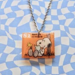 Snoopy postzegelketting met oranje postzegel van Japanse origin en zilveren ketting.