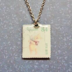 Gouden ketting met vintage Winnie de Poeh postzegel hanger, afgebeeld op Japanse postzegel uit 1984 met groene tekst.